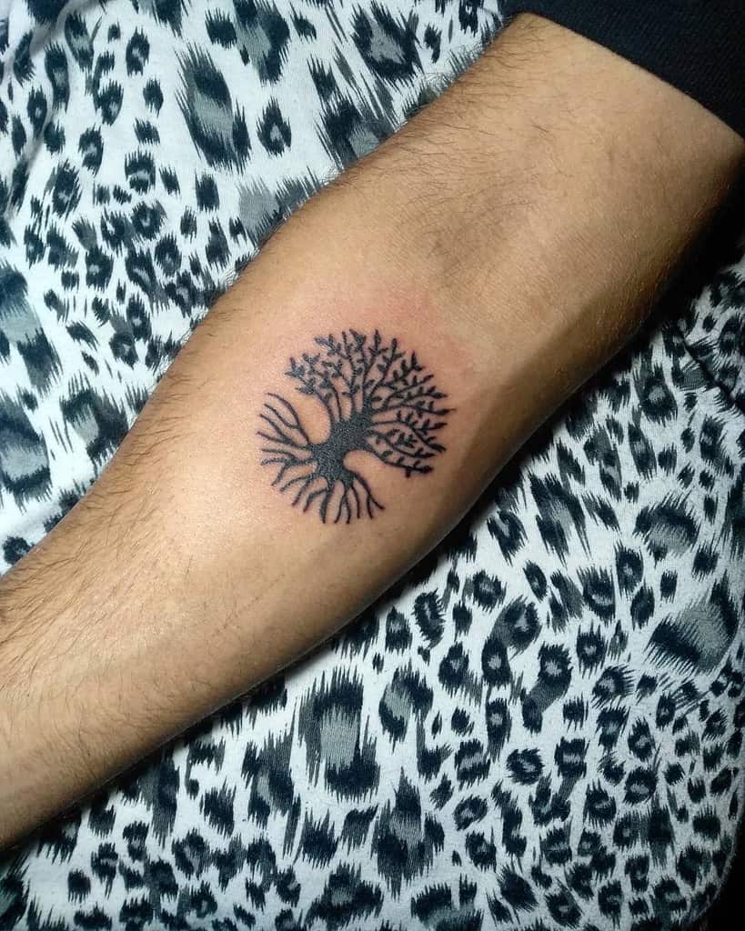 Small and minimalist tree tattoo with intricate branches and roots, symbolizing balance and connection