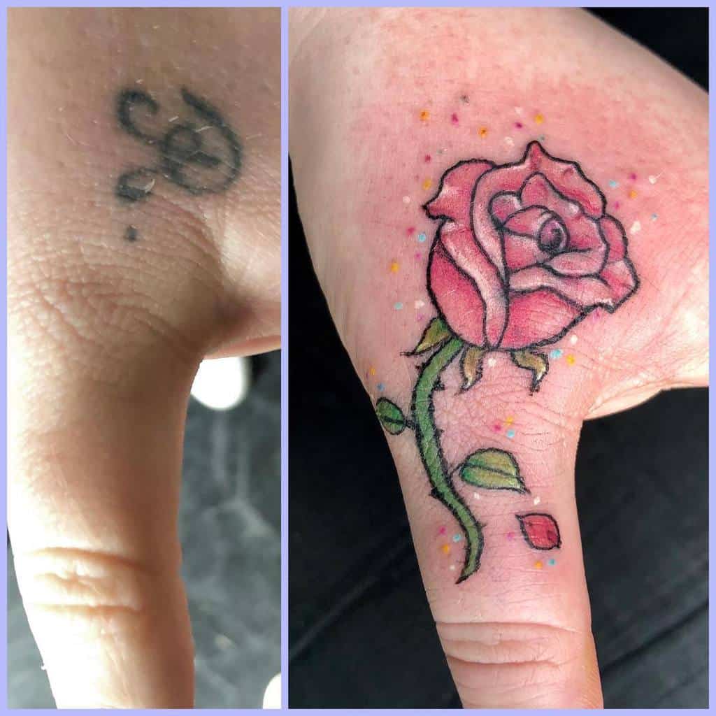 A small, colorful Beauty and the Beast rose tattoo with delicate pink petals, green leaves, and scattered dots, placed on the hand