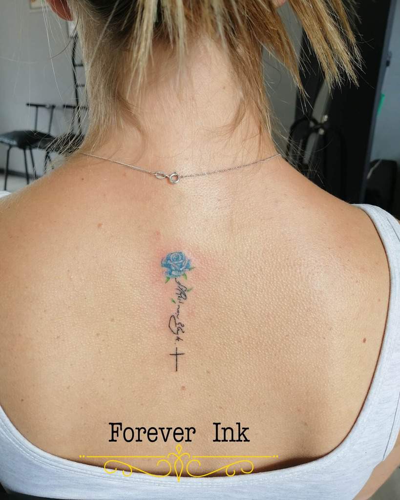 Woman with a small blue rose tattoo on upper back