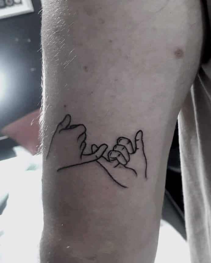 Line art tattoo of two hands making a pinky promise on an arm