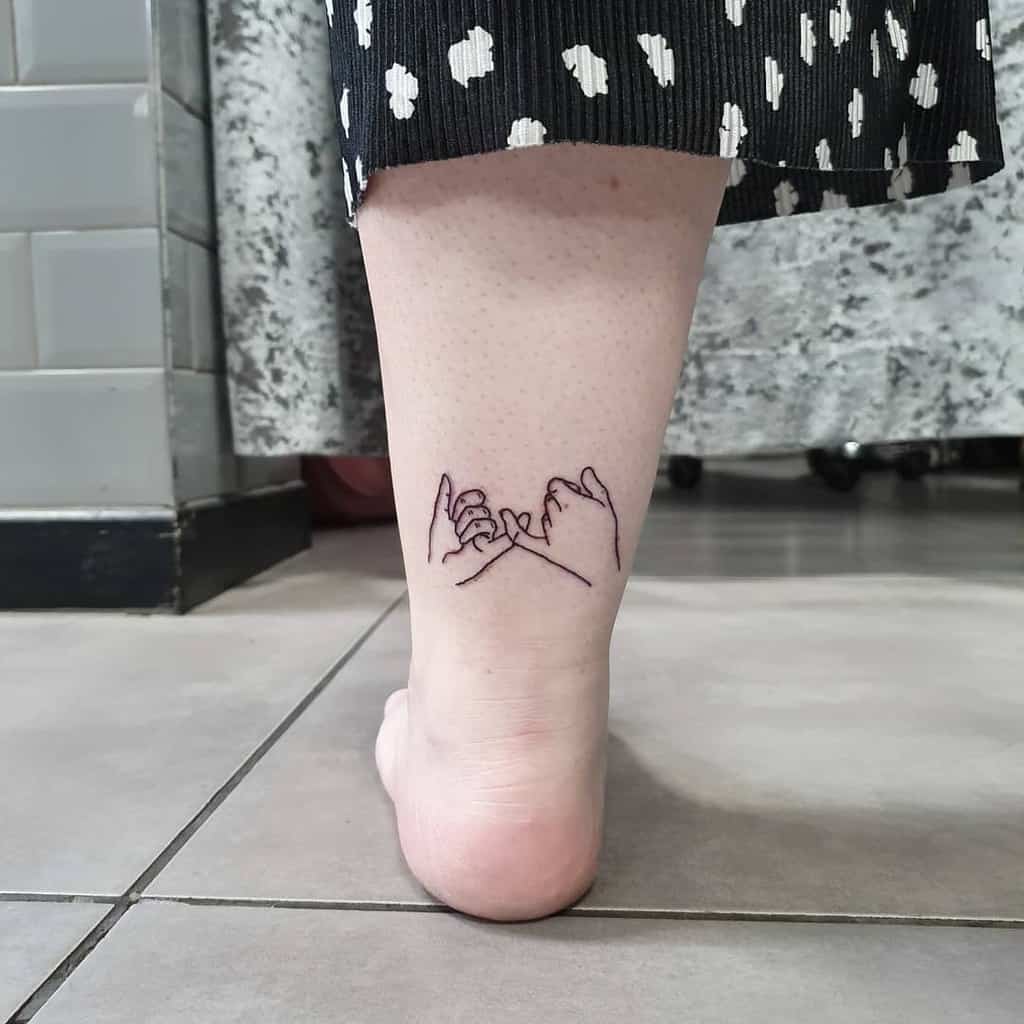 Minimalist pinky promise tattoo with fine line art, placed on the back of the lower leg, just above the ankle