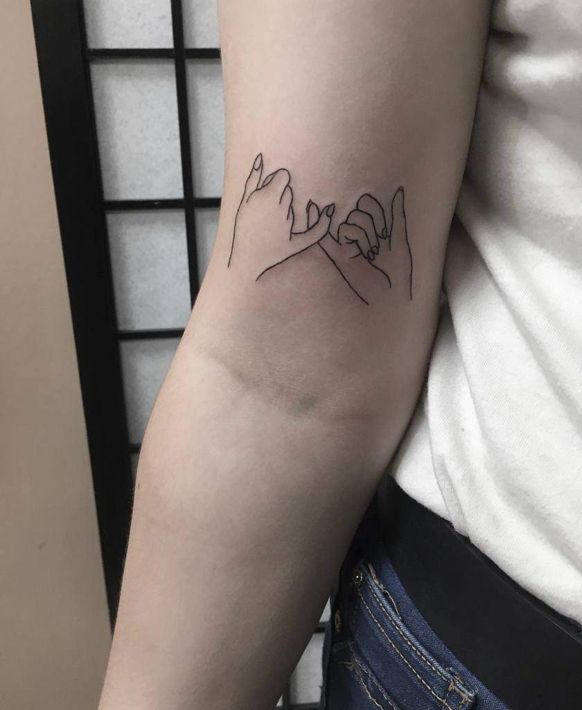 Tattoo of two hands making a pinky promise on the inner arm 