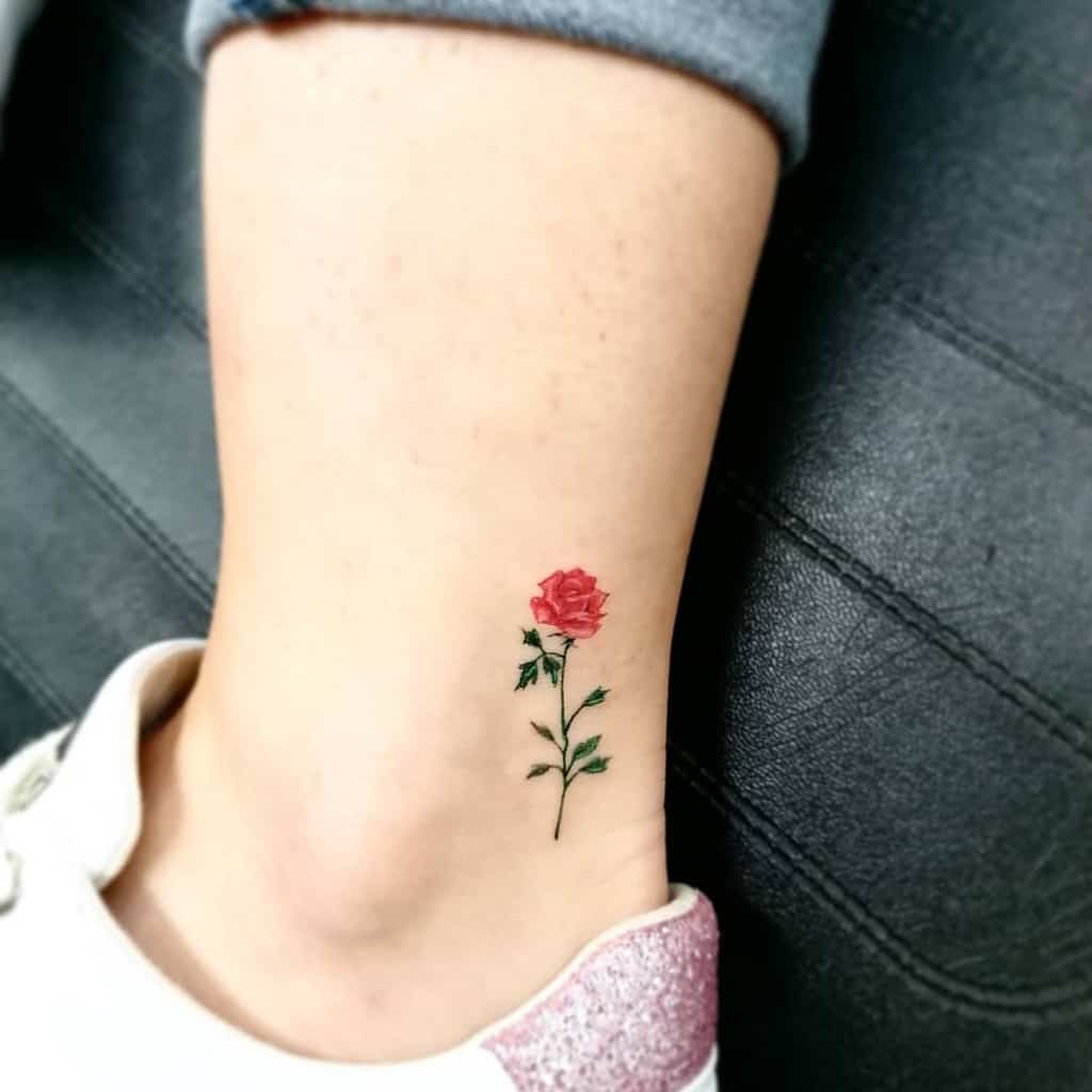 A small vibrant red rose tattoo adorns an ankle