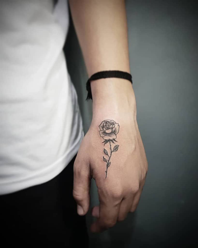 A hand with a black rose tattoo on the back