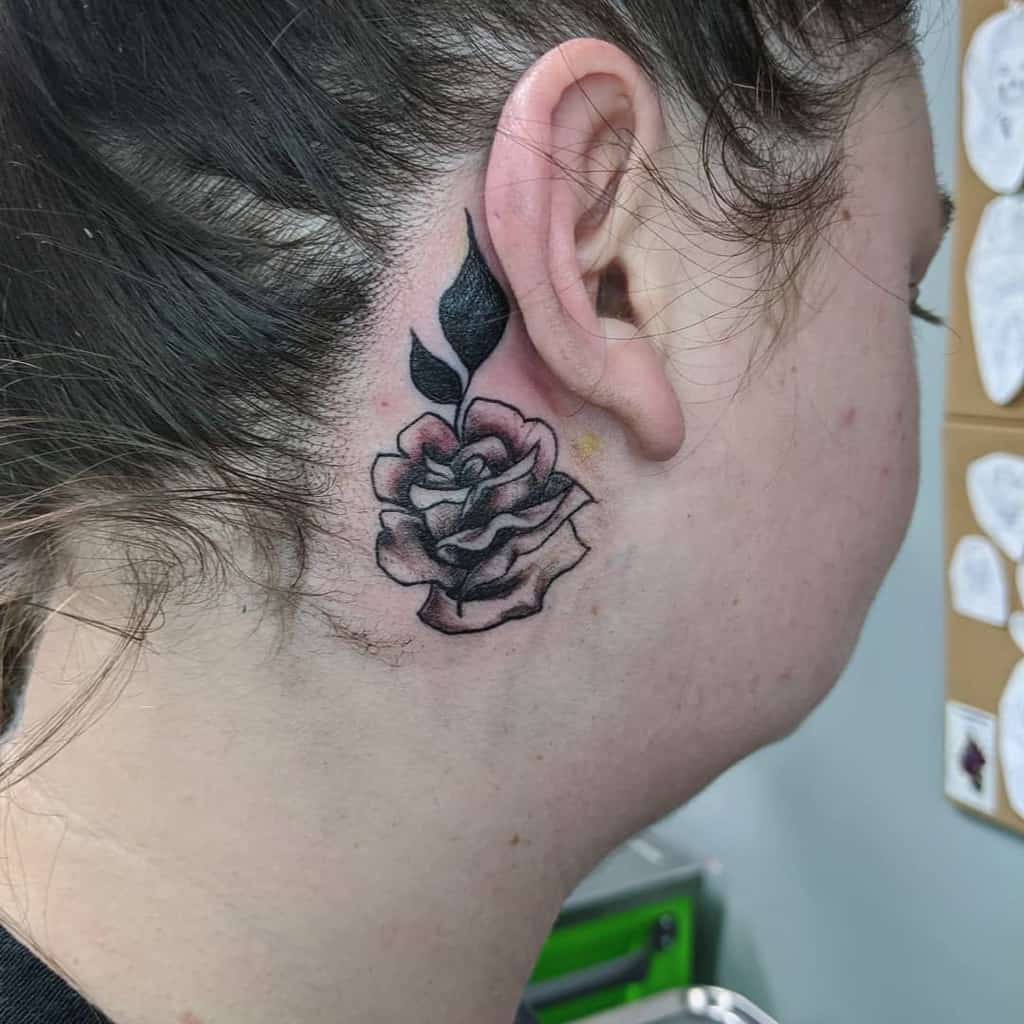 A small rose tattoo behind a woman's ear
