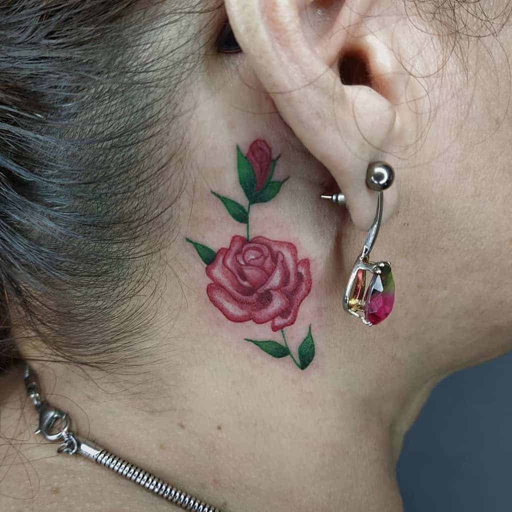 Red rose with green leaves tattoo behind ear
