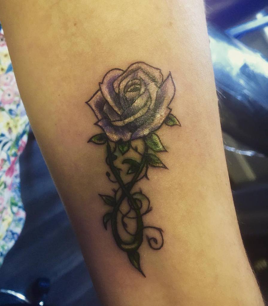 This small and minimalist rose tattoo features delicate vine accents, providing a subtle yet elegant floral design perfect for understated beauty