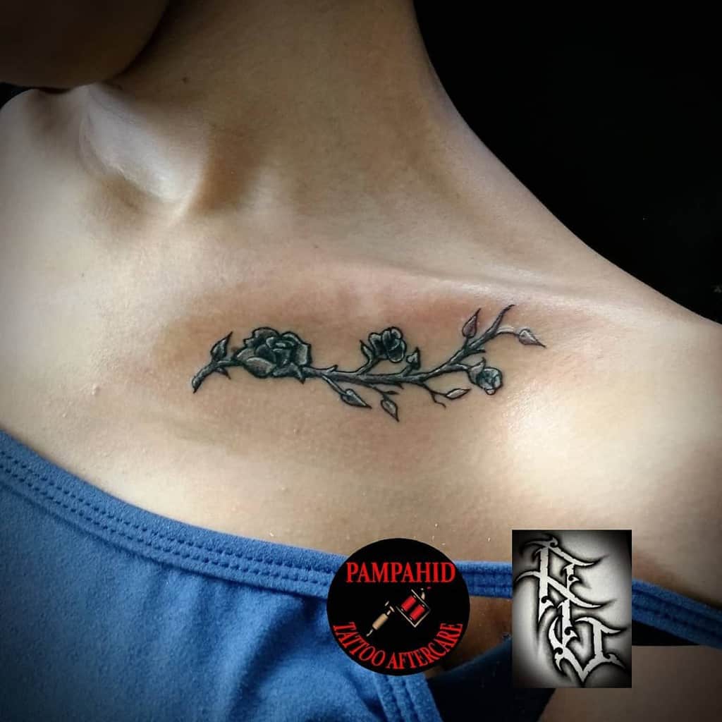 This minimalist rose vine tattoo, placed just below the collarbone, showcases a delicate and intricate design, perfect for a subtle yet meaningful statement