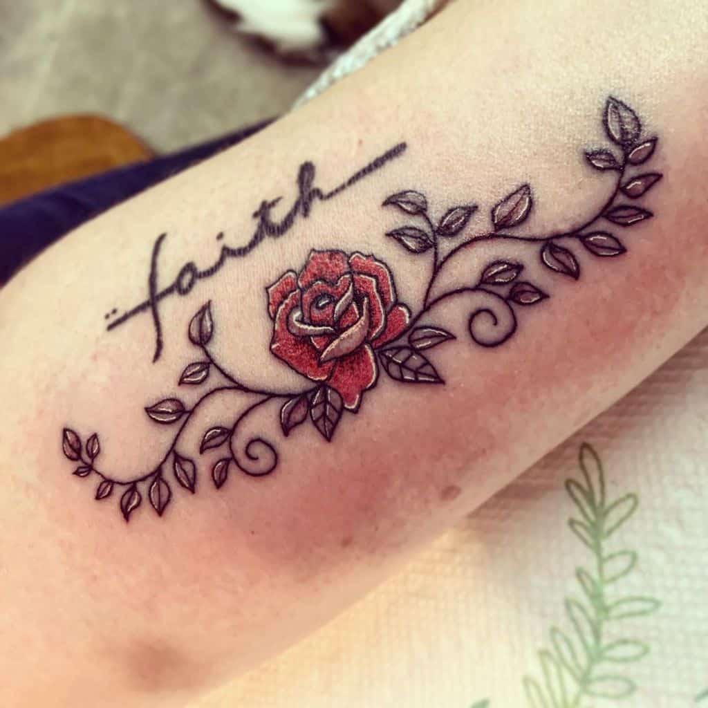 This charming tattoo incorporates the word 'faith' with a vibrant red rose and swirling vines, offering a meaningful and elegant design