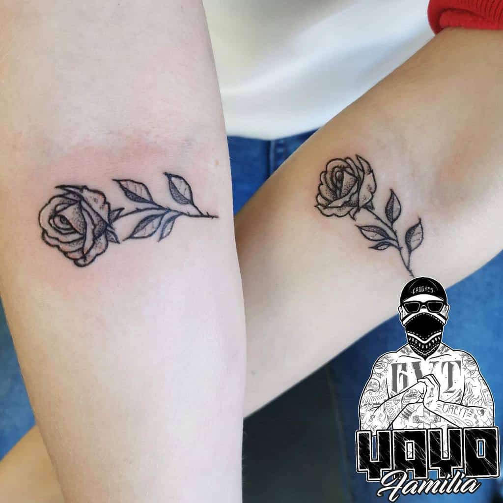 Two small black rose tattoos on forearms 