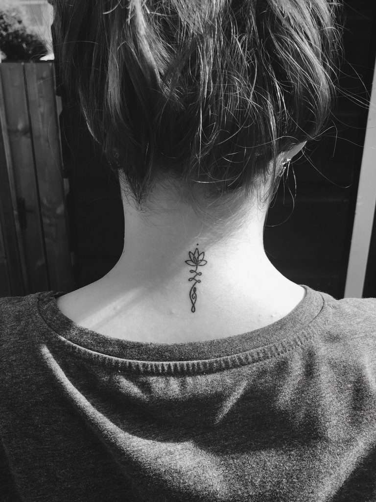 Small Unalome tattoo with a lotus on the nape, symbolizing spiritual enlightenment, growth, and the journey to inner peace.