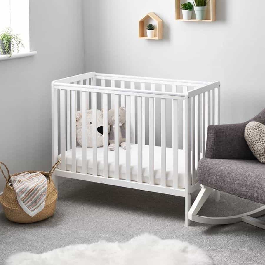 minimalistic nursery white crib gray rocking chair wicker basked teddies