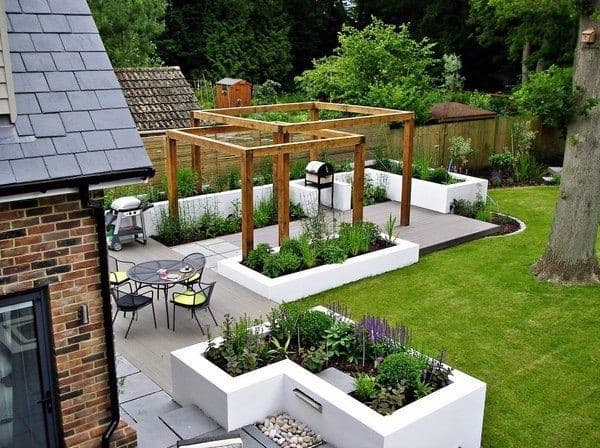 A modern backyard with a wooden pergola, patio, lawn, outdoor seating area, and raised flower beds