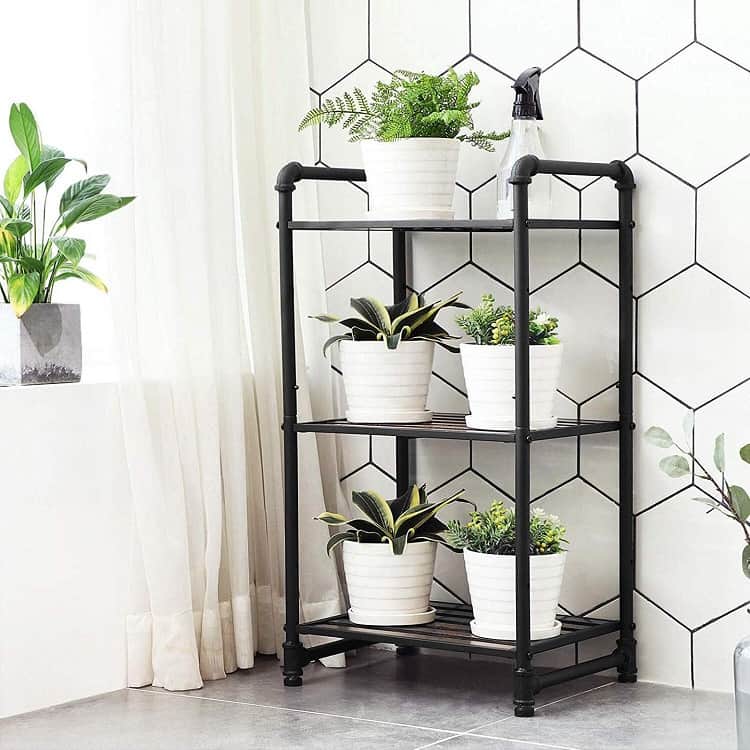 Black metal bathroom shelving unit with white pots and small plants.