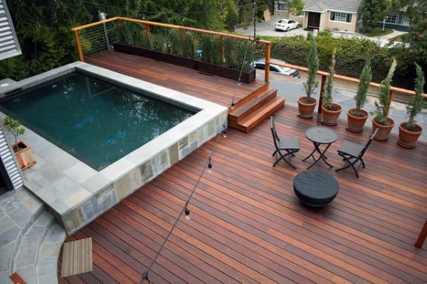 Elevated wooden deck with small pool, potted plants, and outdoor seating area.