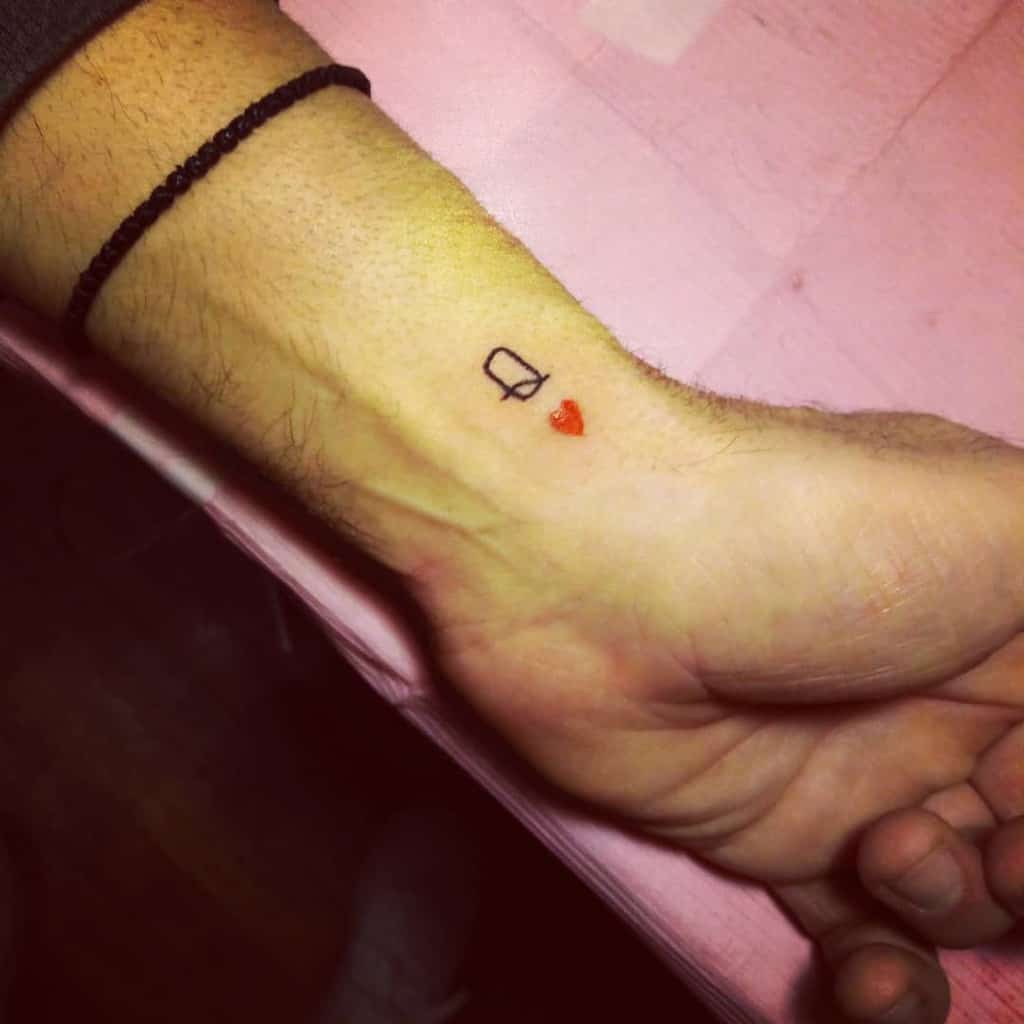 Simple Queen of Hearts wrist tattoo with minimalist black outline and a red heart for a subtle, elegant design