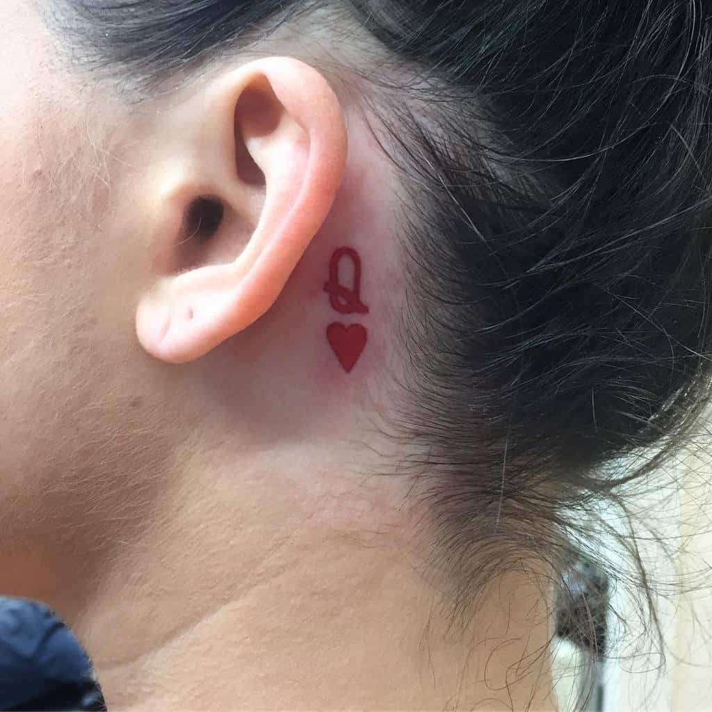 Tiny red queen of hearts tattoo behind the ear