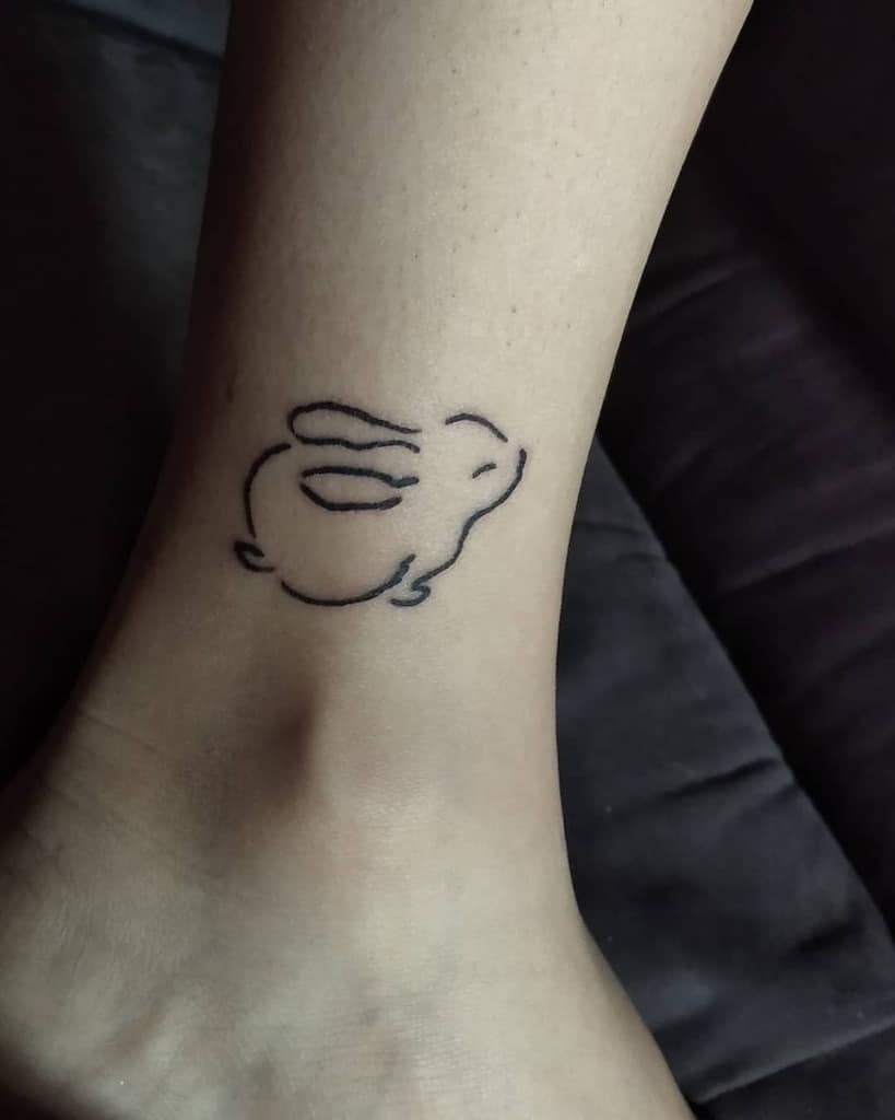 Simple line tattoo of a rabbit in motion, created with minimalistic, fluid lines