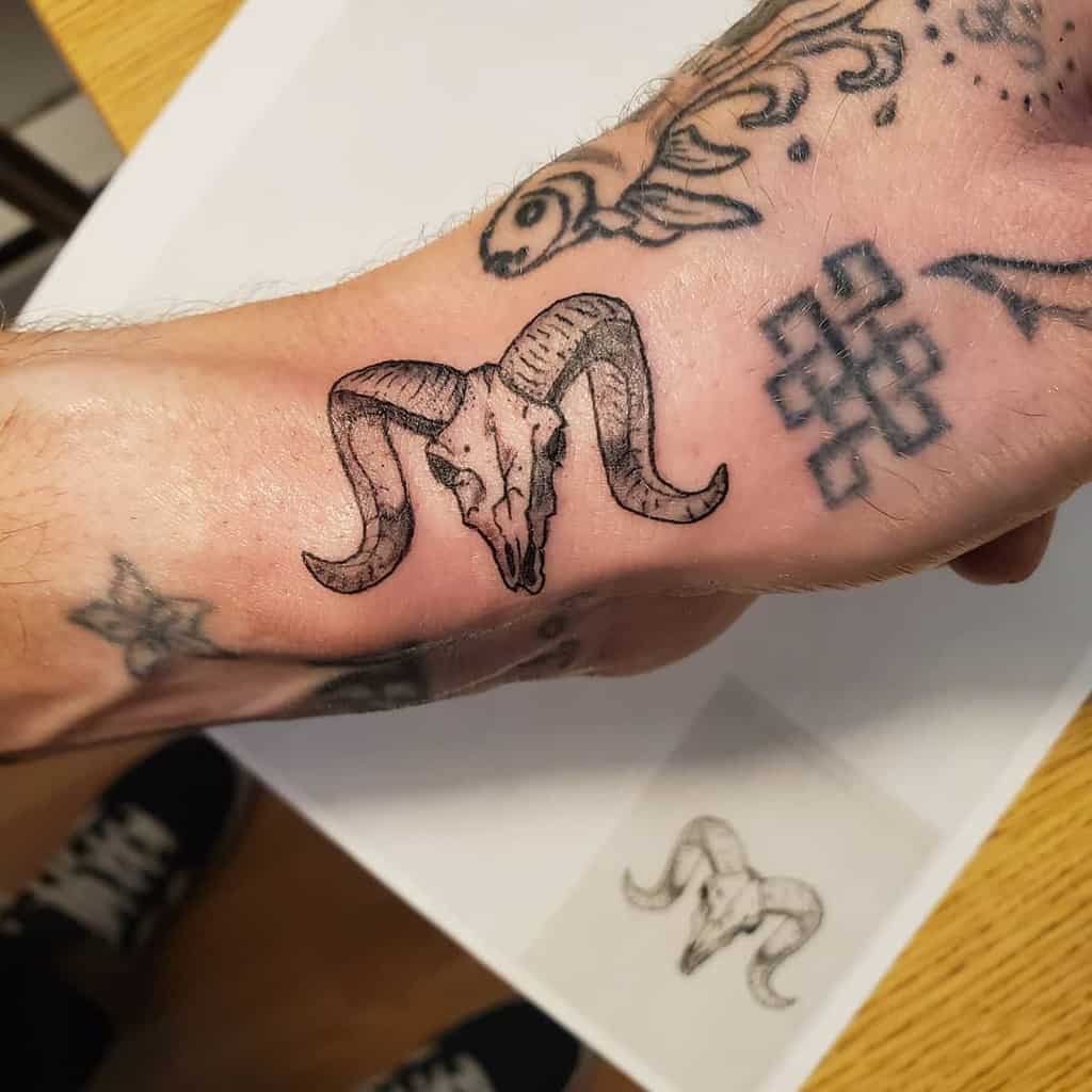 A small tattoo of a ram skull on a person's arm