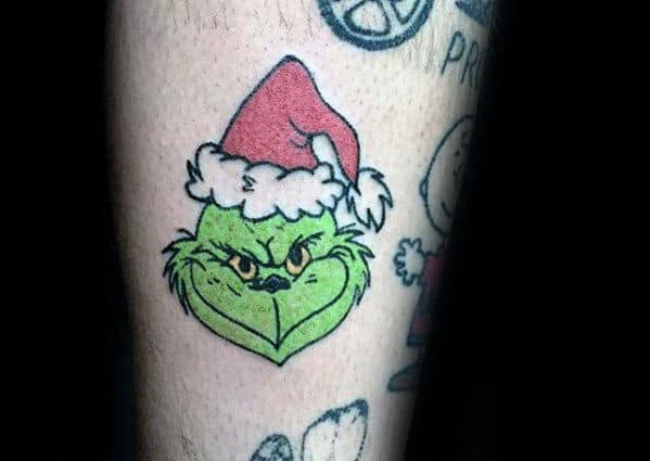 Grinch with an angry expression, wearing a red Santa hat, outlined in bold black lines and filled with vibrant green and red tones, creating a playful tattoo design.