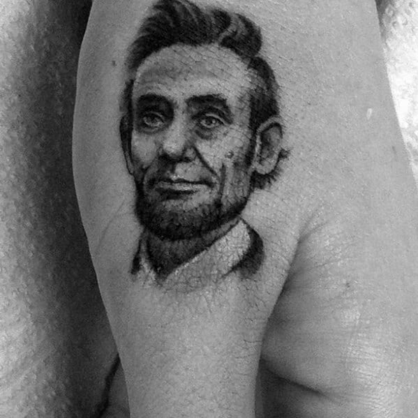 Black and white tattoo of a bearded man's face, resembling Abraham Lincoln