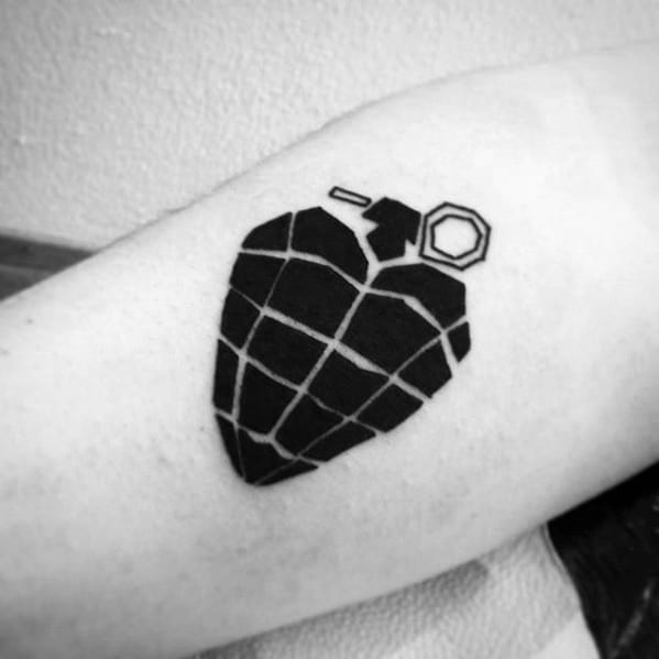 Minimalist black tattoo of a heart-shaped grenade, inspired by Green Day’s *American Idiot* album artwork.