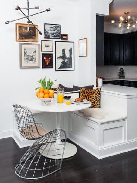 Cozy nook with a round table, modern chairs, wall art, and fresh oranges