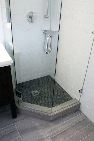 Corner glass shower with gray hexagonal tile floor and sleek white subway tile walls