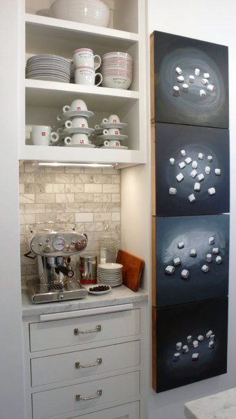 Compact coffee bar with white cabinets, marble backsplash, open shelves, and espresso machine.