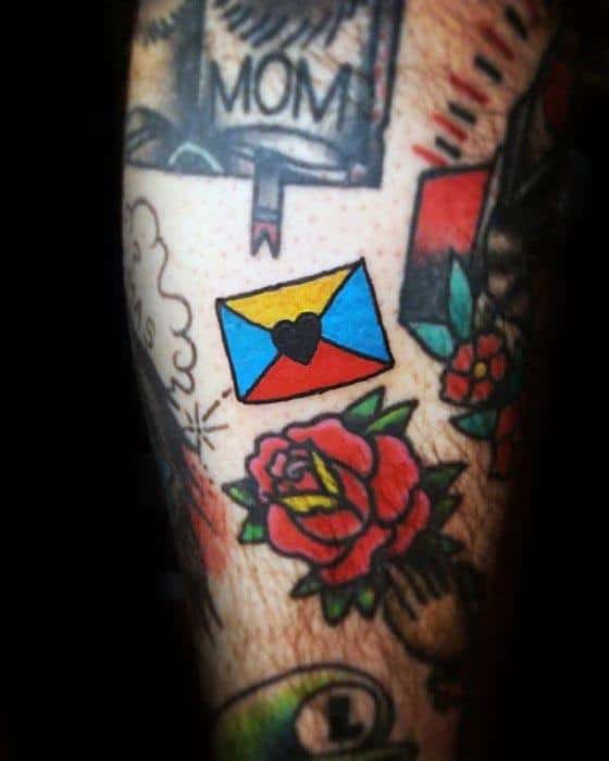Tattoo of a vibrant envelope with a heart and rose on someone's skin