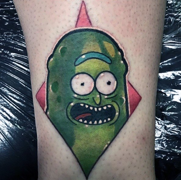Pickle Rick tattoo with a bold geometric red diamond background, featuring a vivid expression and smooth green shading on the leg.