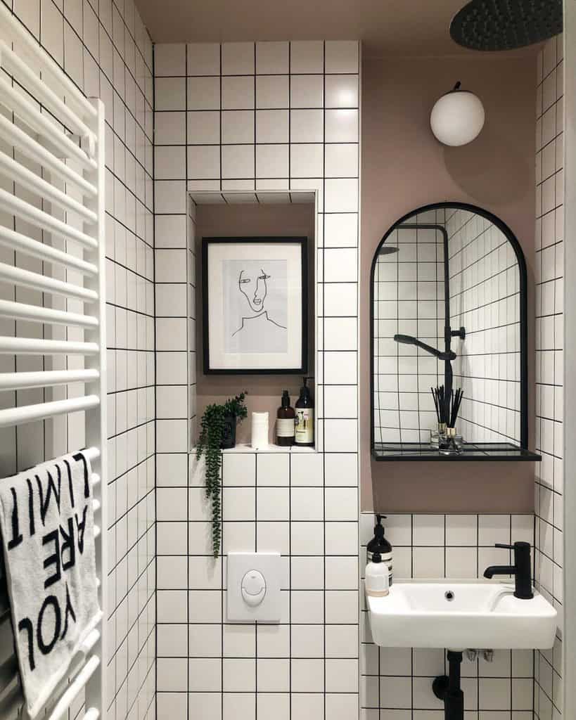 modern guest bathroom white tiles black grout white sink black accents wall mirror