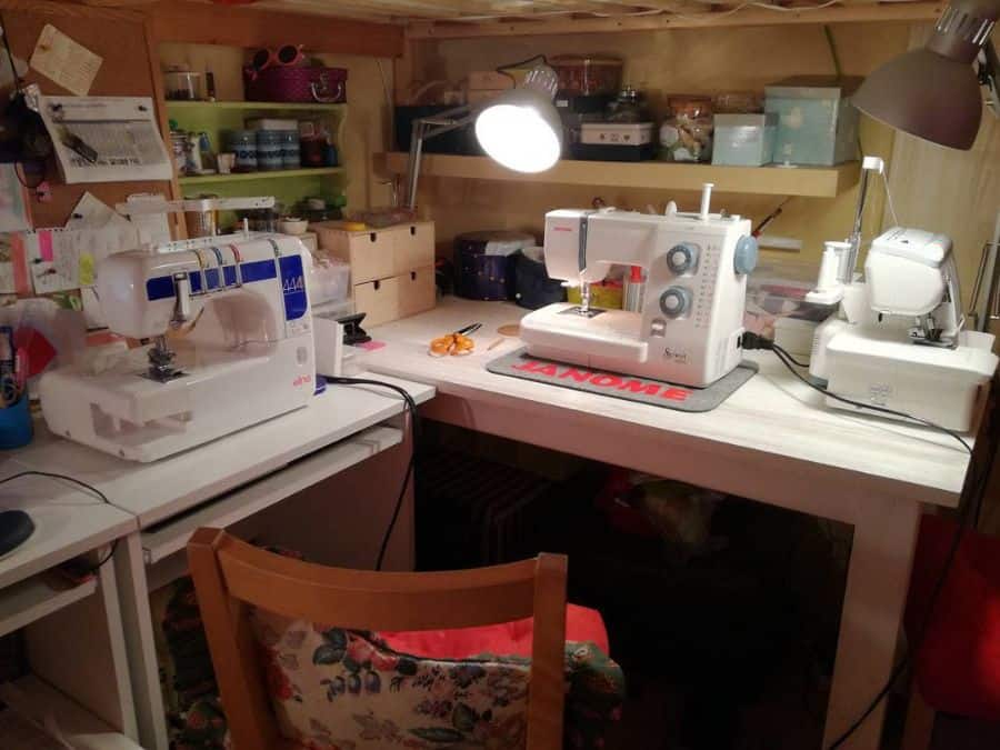 Cozy sewing workspace with multiple machines, organized shelves, warm lighting, and a creative atmosphere