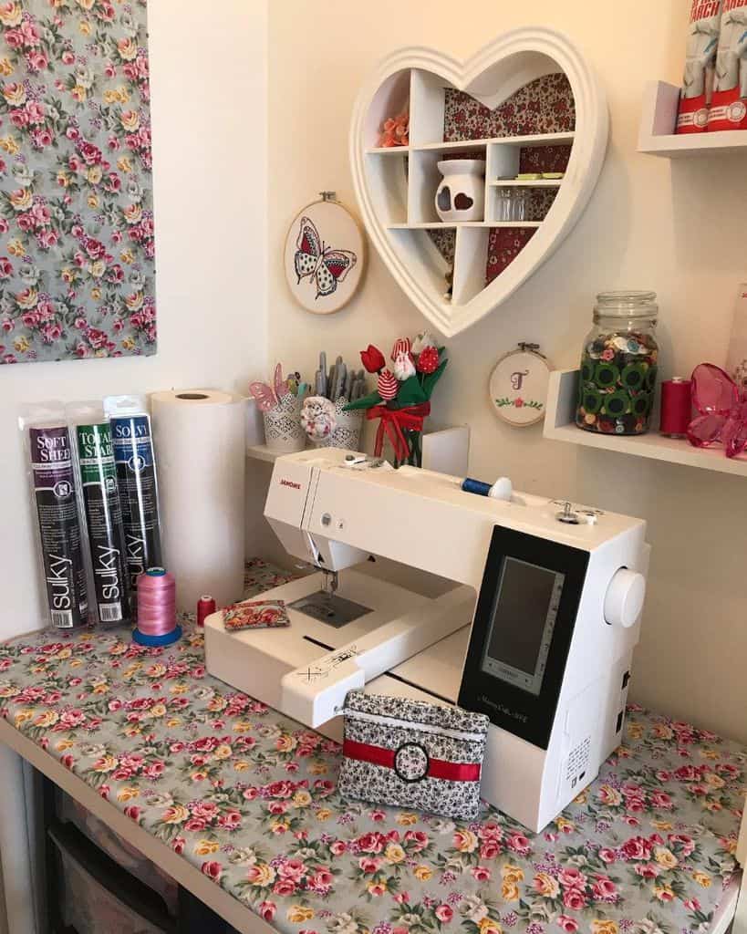 Elegant sewing corner with floral decor, heart-shaped shelf, colorful threads, and a modern sewing machine