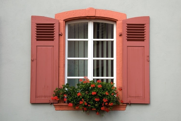 small stucco exterior window trim with red wooded shutters planter