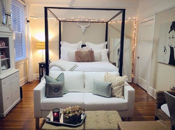 Cozy studio with a canopy bed, soft lighting, and a compact sofa for a warm, inviting vibe.