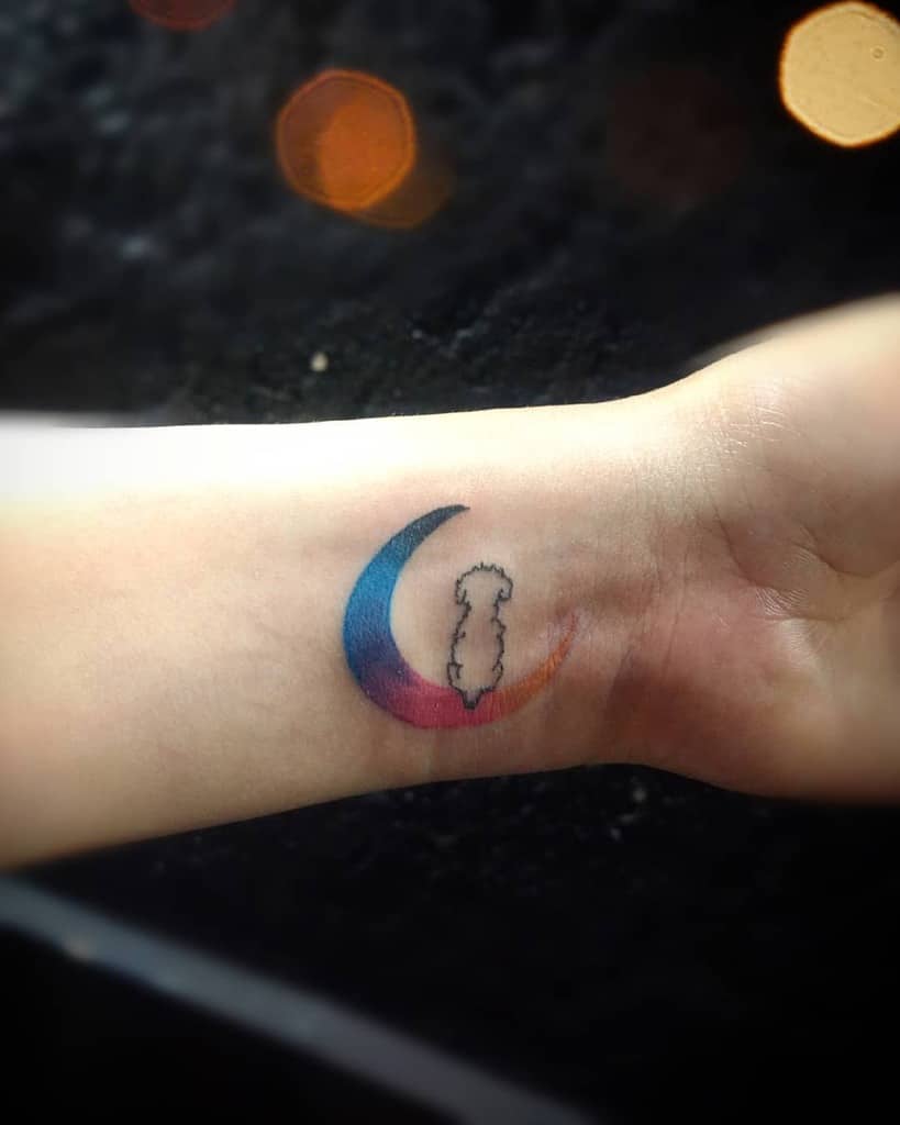 Minimalist tattoo featuring a colorful crescent moon blending blue, pink, and orange hues, with a fine-line silhouette of a dog inside
