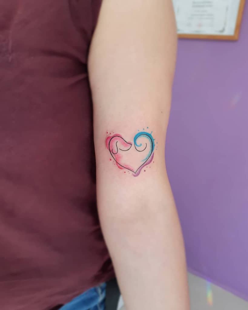 Colorful watercolor-style tattoo of a heart formed by abstract dog silhouette, blending red, pink, and blue hues