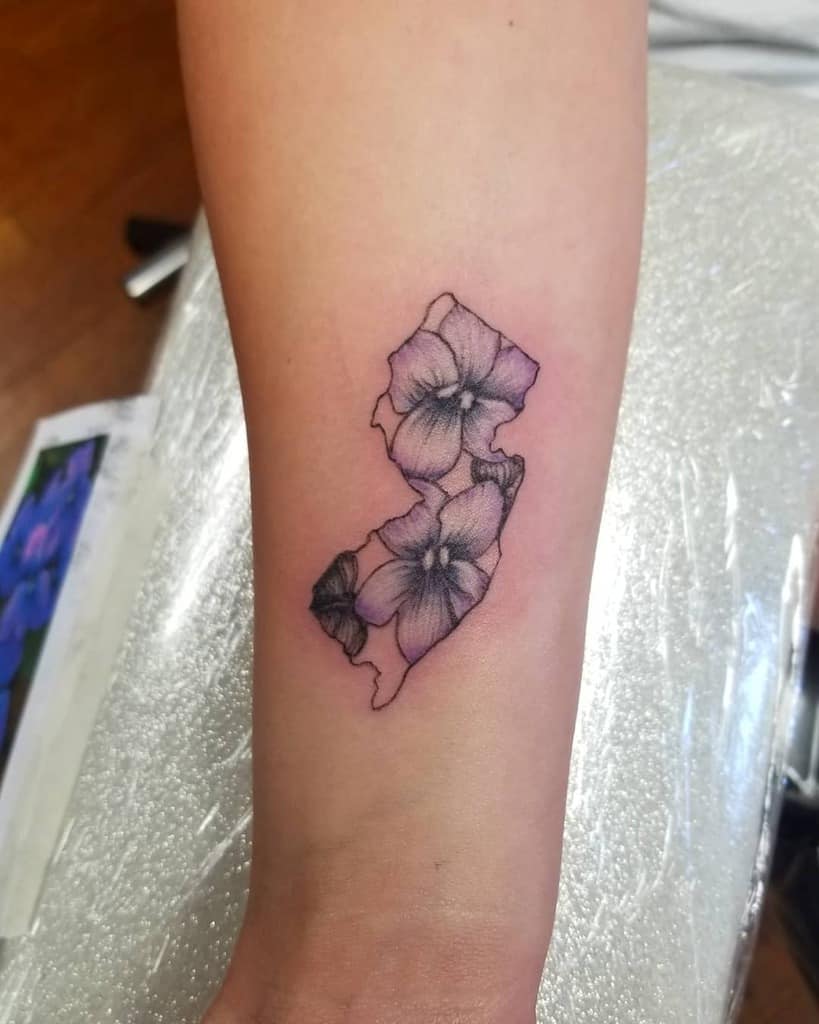 Unique tattoo featuring violet flowers blended into the outline of New Jersey, symbolizing state pride and natural beauty