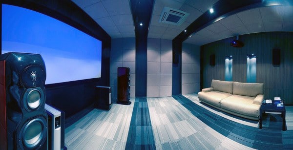 Home theater with a large screen, speakers, and a beige sofa in a modern, blue-lit room