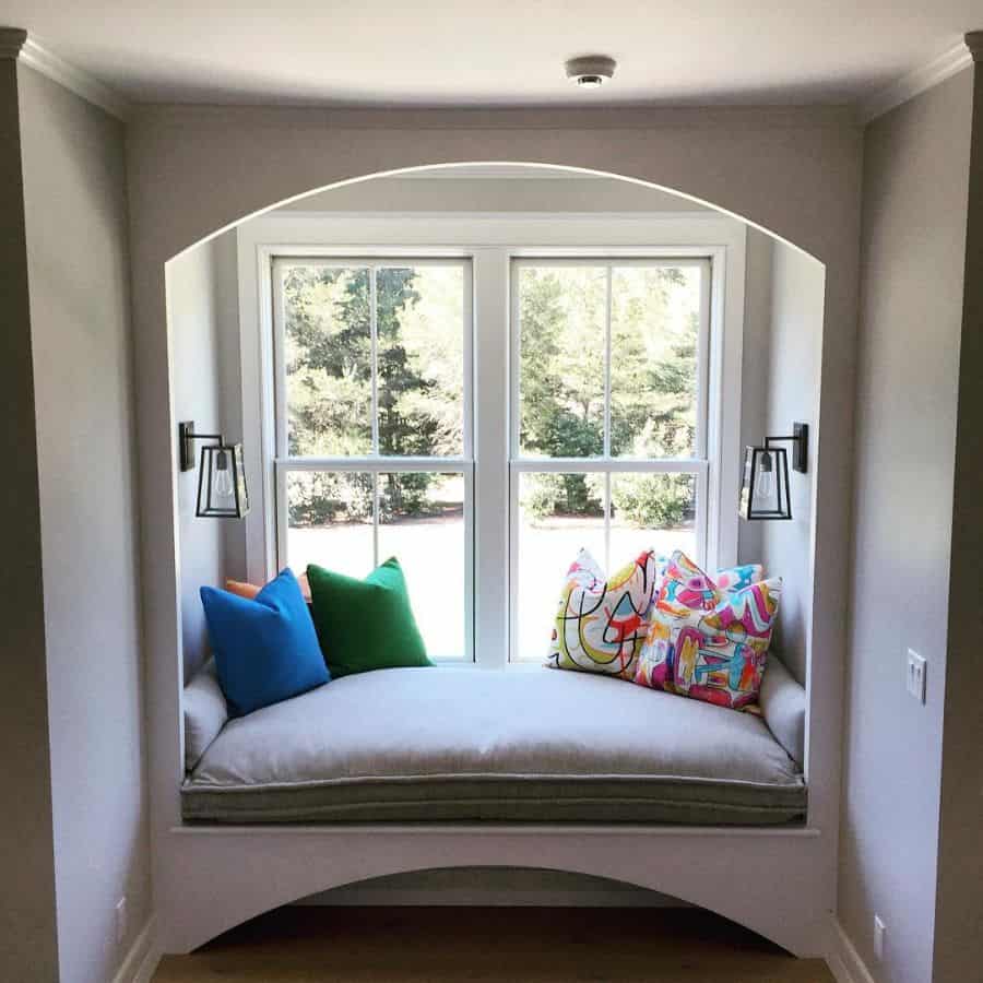 small window seat colorful pillows sconces lights