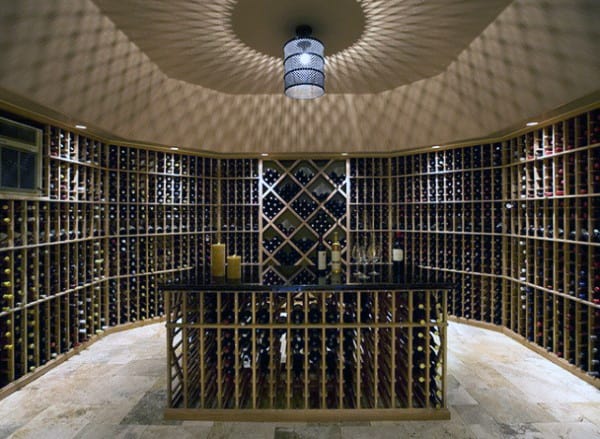 A dimly lit wine cellar with shelves of fine wine bottles and a central table adorned with glasses and candles