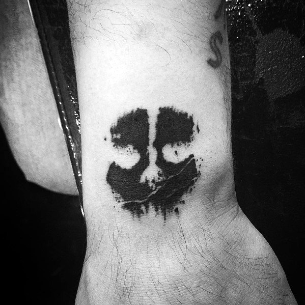 Minimalist Call of Duty Ghosts skull tattoo on the wrist, featuring a bold black ink stencil design with a distressed and rugged look.