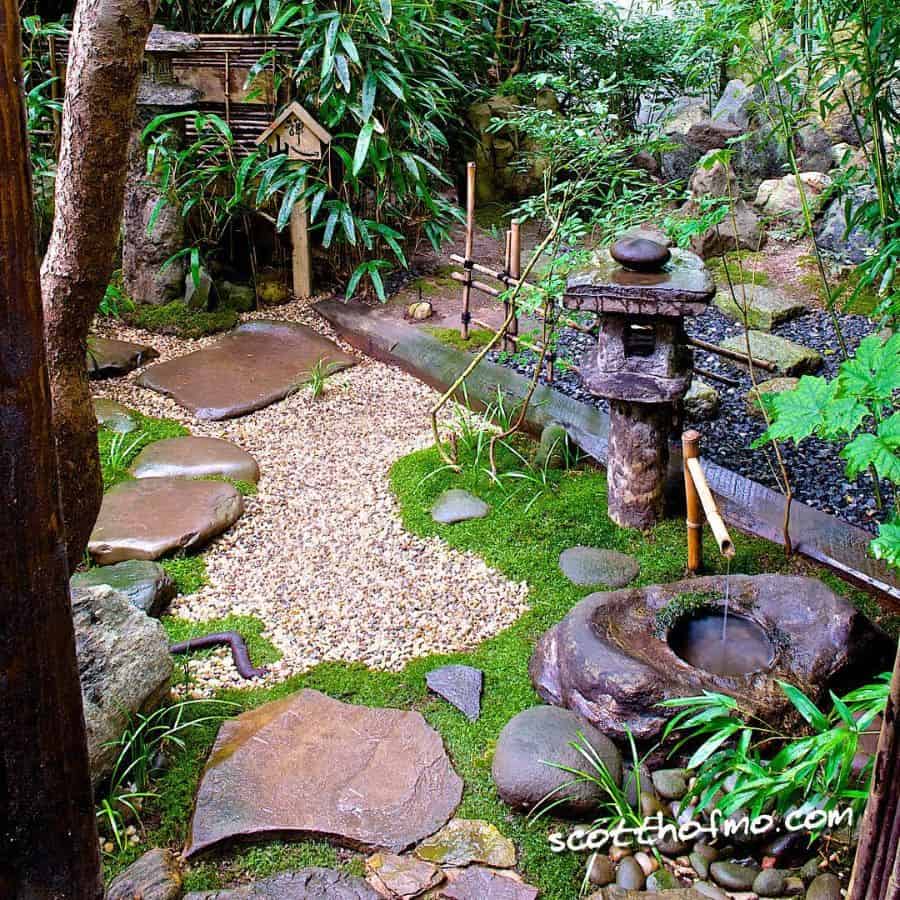 small japanese garden with water featue stone temple statue 