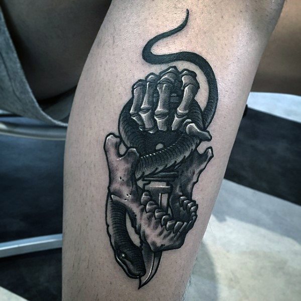 Black and grey tattoo featuring a snake, skeletal hand, and dagger, with bold shading and intricate details for a dark, realistic design.