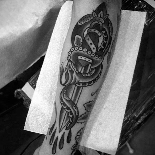 Black and grey snake and dagger tattoo on forearm, featuring bold shading, intricate details, and blood drops for a striking traditional design.