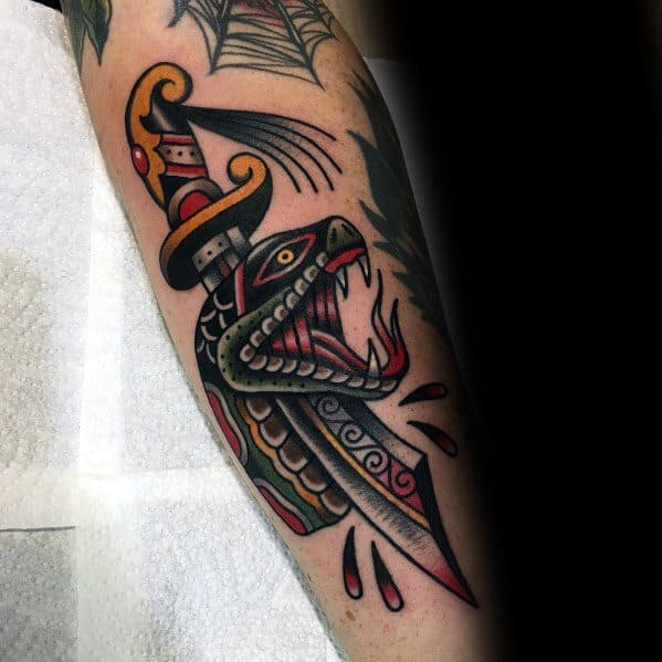 Traditional snake and dagger tattoo on forearm, featuring bold black, red, and yellow ink with intricate shading and blood drop details.