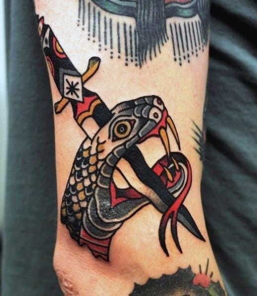 Traditional snake and dagger tattoo on forearm, featuring bold black, red, and yellow ink with intricate scales and a fierce old-school design.