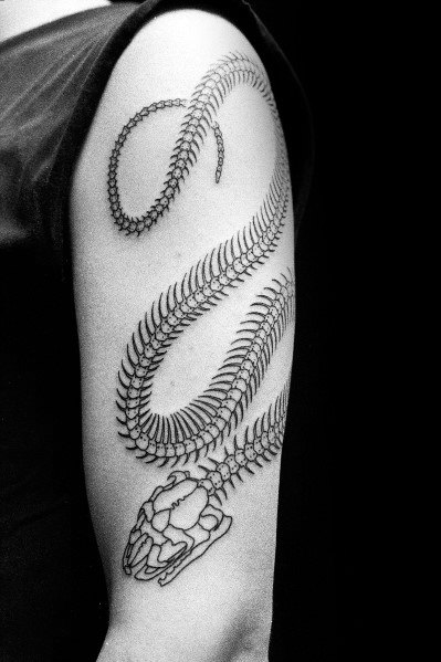 Snake skeleton tattoo on the upper arm, featuring a detailed skull and ribcage with a flowing design for a bold and intricate look.