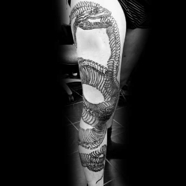 Snake skeleton tattoo wrapping around the entire leg, featuring intricate rib details and a bold, flowing design for a striking visual effect.